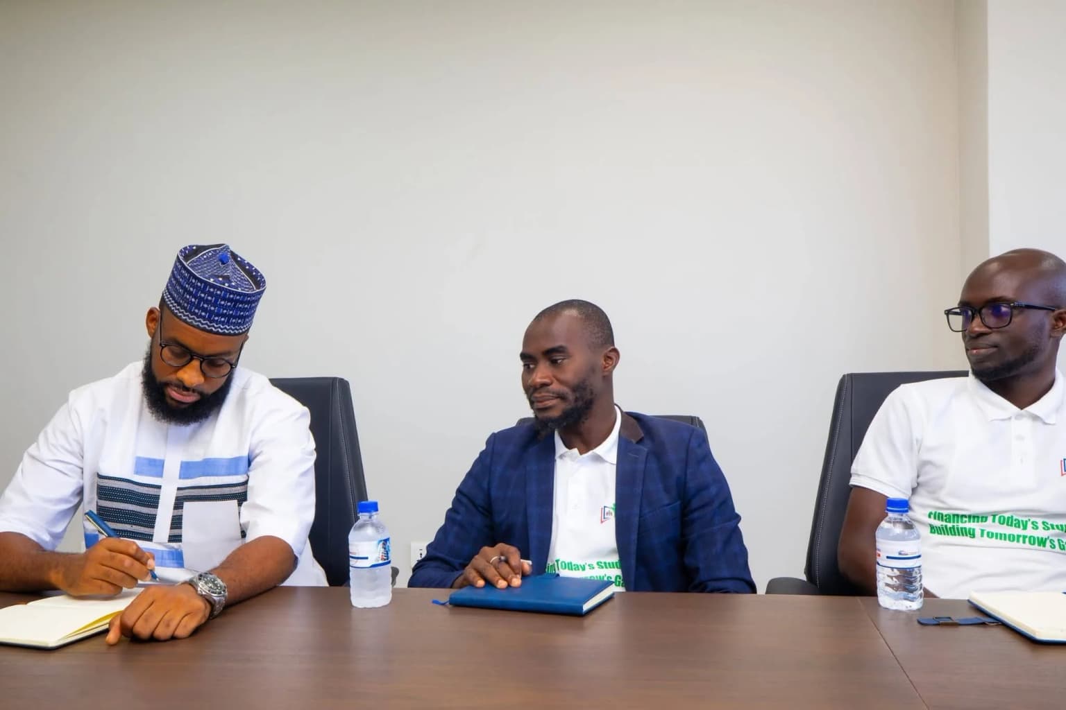Three members of the SRLS team at a meeting table, two of them wearing shirts that carry the Scheme's tagline.